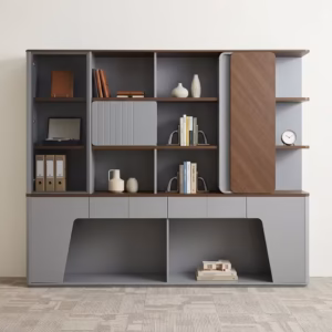 Premium Executive Modern Office Wooden Cabinet in a dual-tone matte grey and walnut woodgrain finish, showcasing a tinted smoked-glass case on the left, open book shelves with a grey ribbed sliding door, a vertical rounded wood panel block on the right next to open side shelving with a pen holder, and lower push-open drawers above a geometric open base cutout, standing on grey textured office carpet tiles.