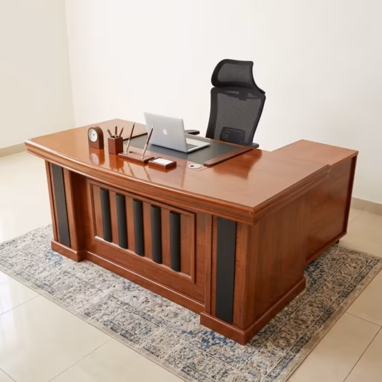 Executive 160cm L-Shaped Office Desk in a rich cherry wood finish with black leather desk padding and a decorative panel front, paired with an ergonomic chair.