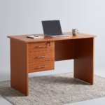 1M 3-Drawer Home/Office Study Desk in a warm oak wood grain finish featuring a lockable top drawer, sleek metallic handles, and an open knee space on a patterned rug.