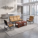 Premium Executive 5-Seater Reception Sofa Set featuring a 3-seater tandem sofa and two single-seater armchairs upholstered in tan segmented leatherette with chrome cantilever frames and dark wood armrests, arranged around a matching rectangular wooden two-tier coffee table on a polished concrete floor inside a modern corporate office lobby.