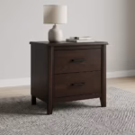 Close-up view of a 2-Drawer Wooden Side Bed Table in an espresso finish, highlighting its modern matte-black hardware on a cream rug.