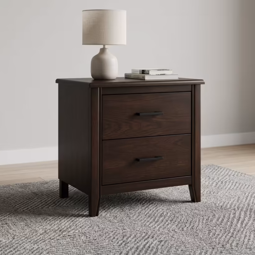 Close-up view of a 2-Drawer Wooden Side Bed Table in an espresso finish, highlighting its modern matte-black hardware on a cream rug.